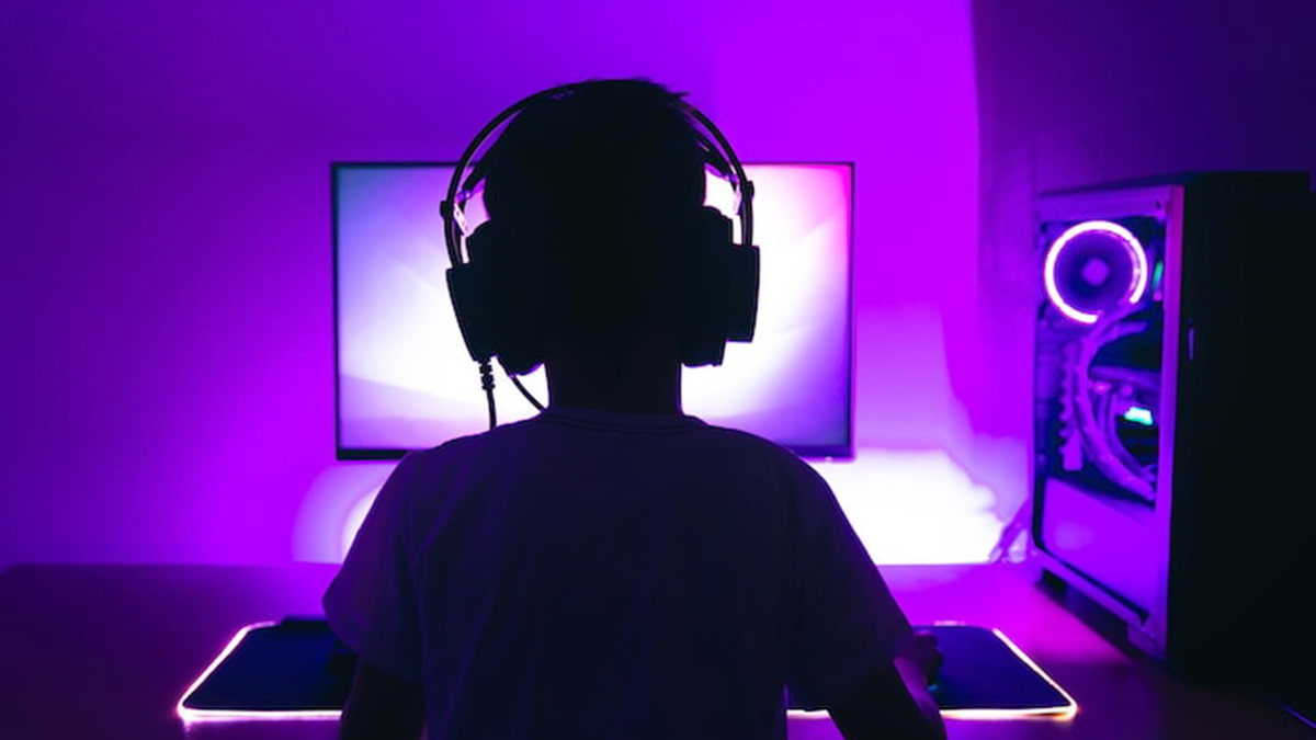 Image showing a silhouette of a gamer playing the best browser games on PC, backlit by a purple and pink lights.